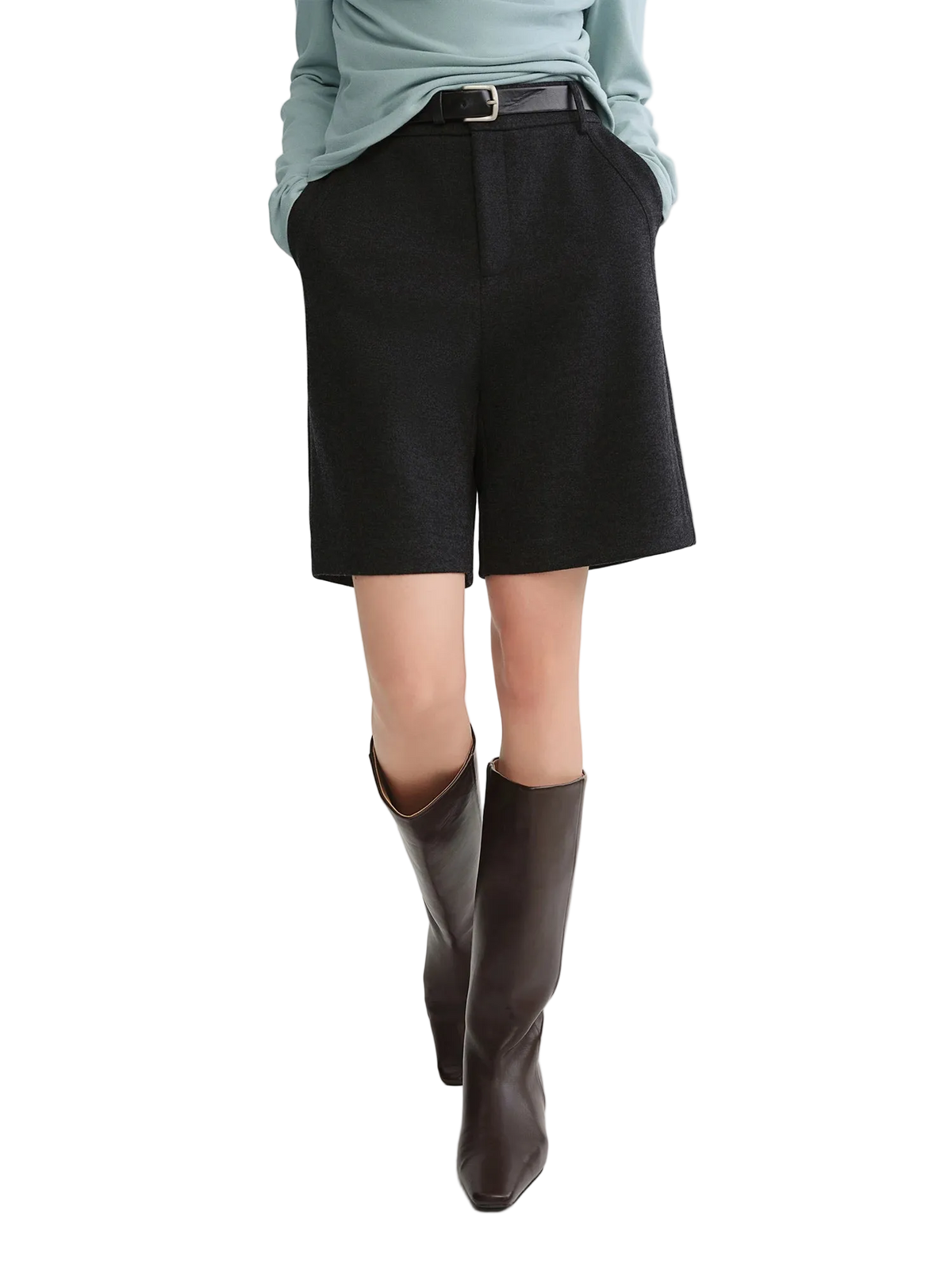 Person wearing black shorts and brown boots on a white background